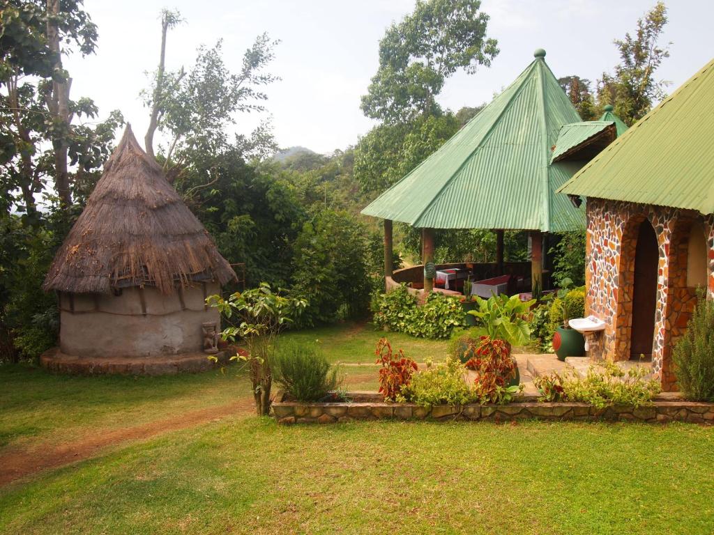 Songota Falls Lodge في أروشا: منزل بسقف عشبي ومبنى صغير