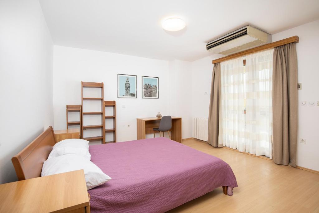 1 dormitorio con cama morada y escritorio en Villa Arena - pool table, table tennis, darts & more, en Pula