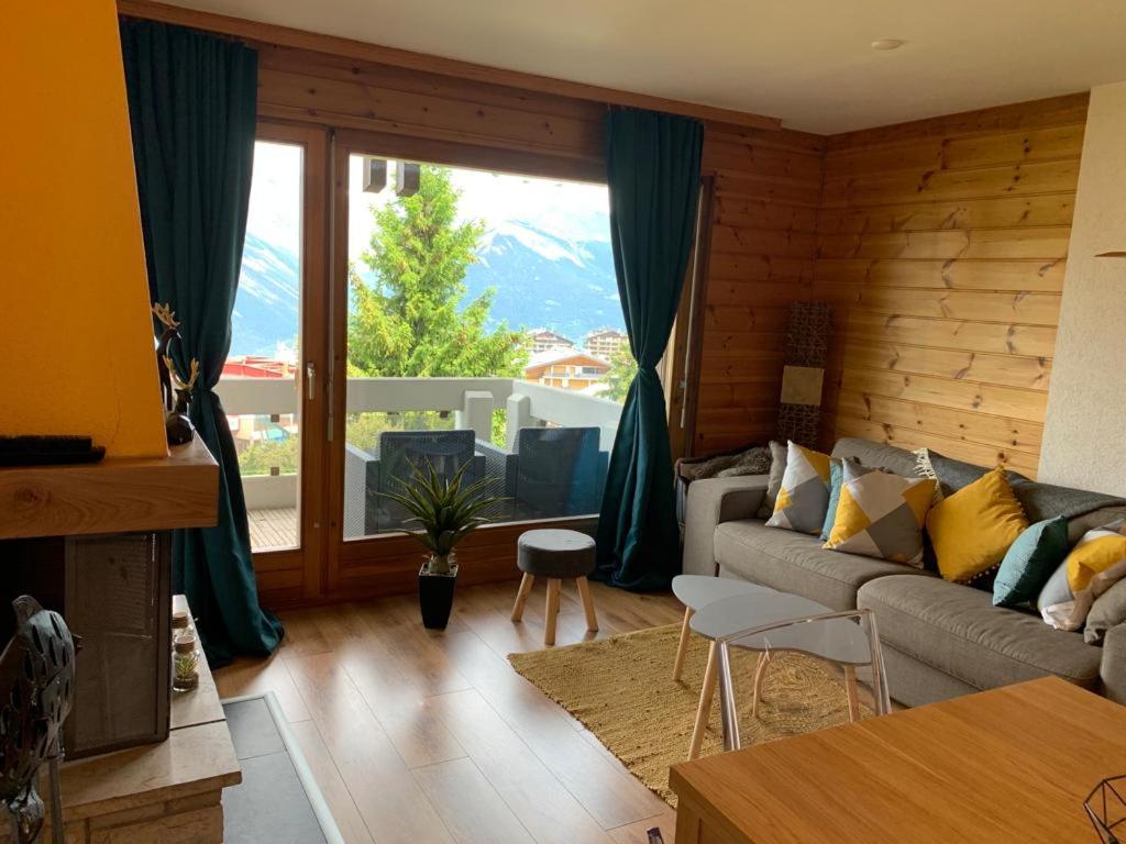 a living room with a couch and a large window at Studio Hauts-de-Nendaz G2 ski in-out in Nendaz