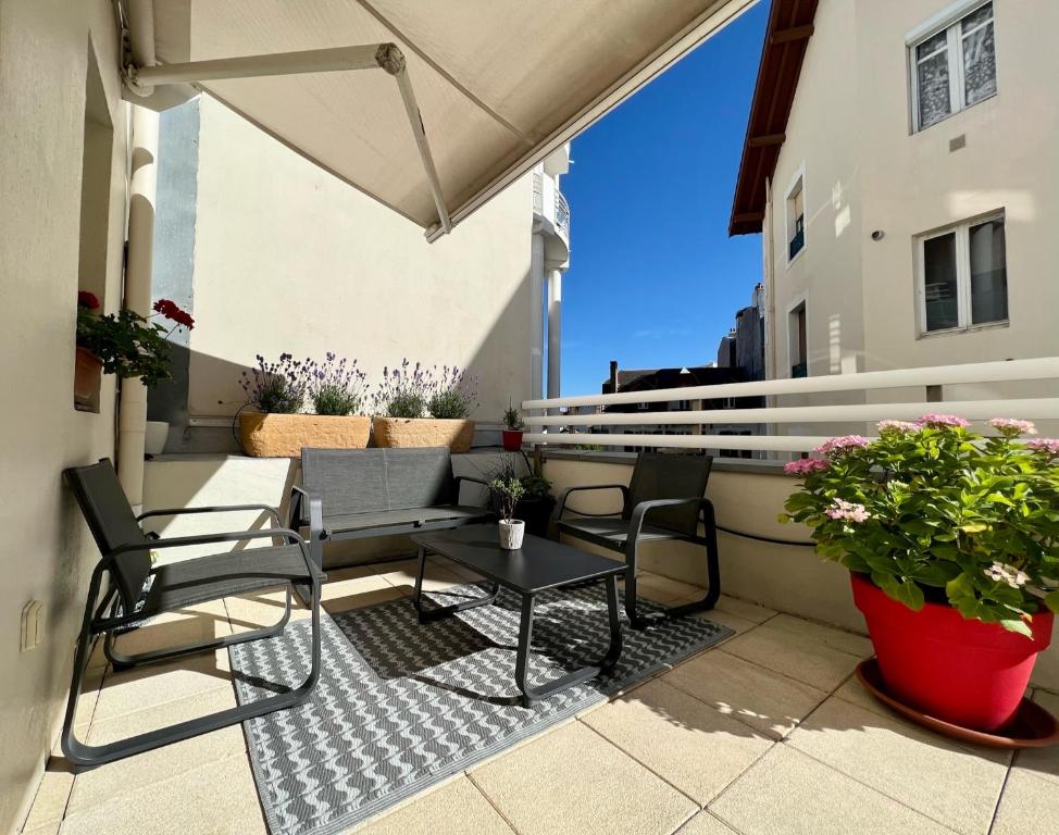 een patio met stoelen en een tafel op een balkon bij 120m2 avec deux terrasses ensoleillées à Biarritz in Biarritz