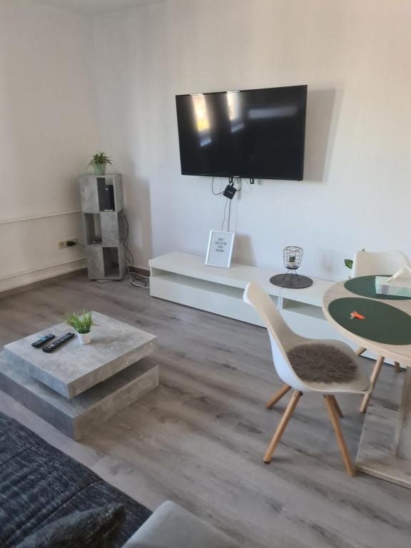 un soggiorno con TV, tavolo e sedie di Apartment für Monteure Nr 3 a Kassel
