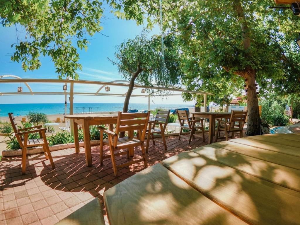 un patio con mesas y sillas y el océano en Naz Beach Bungalow Hotel in Antalya, en Kızılot