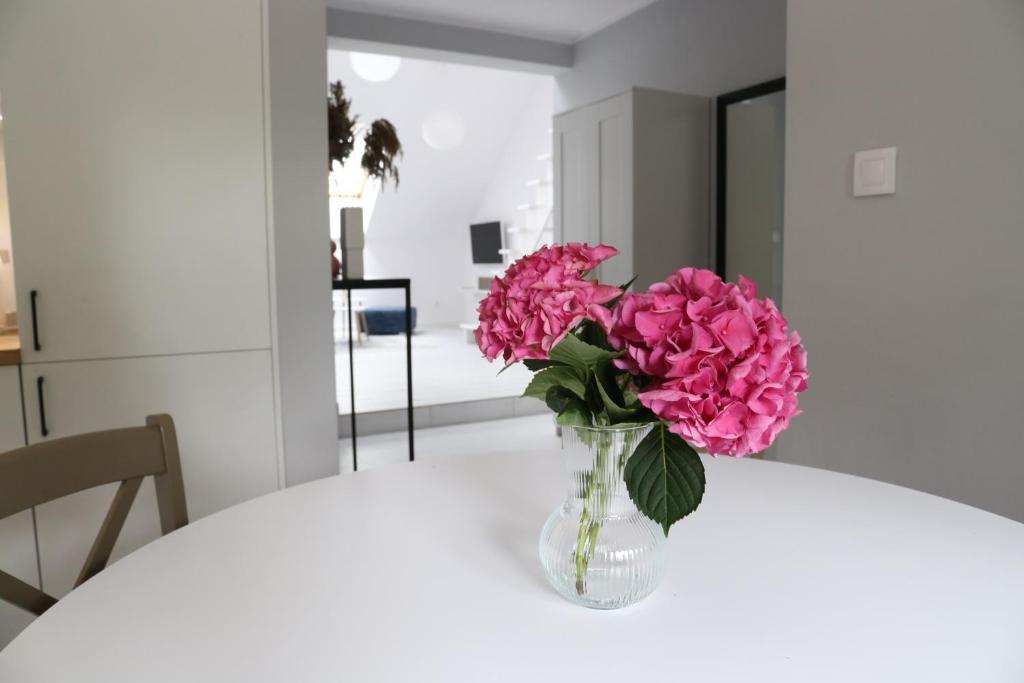 un vaso pieno di fiori rosa seduto su un tavolo di Komfortowe mieszkanie z antresolą a Barczewo