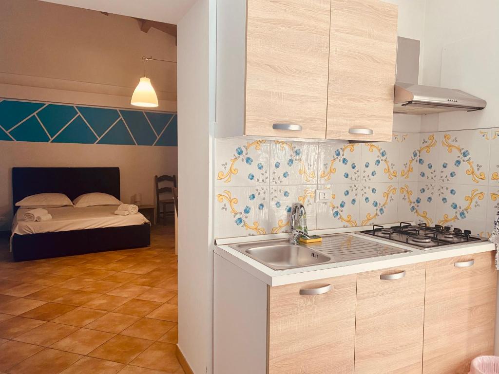 een keuken met een wastafel en een slaapkamer met een bed bij Cartari Apartment in Palermo