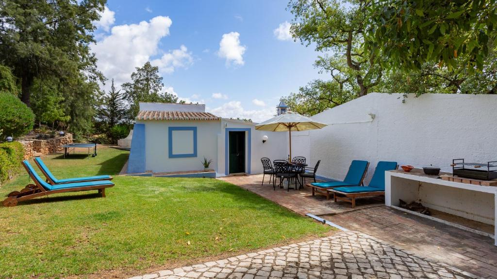 une terrasse avec des chaises et un parasol ainsi qu'une maison dans l'établissement Charming House in a Vineyard Near the Beach, à Porches