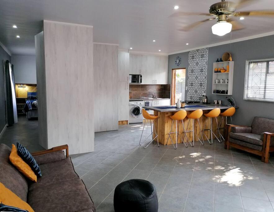 uma sala de estar com um sofá e uma cozinha com um bar em Greystoke - Furnished, self service apartment. em Springs