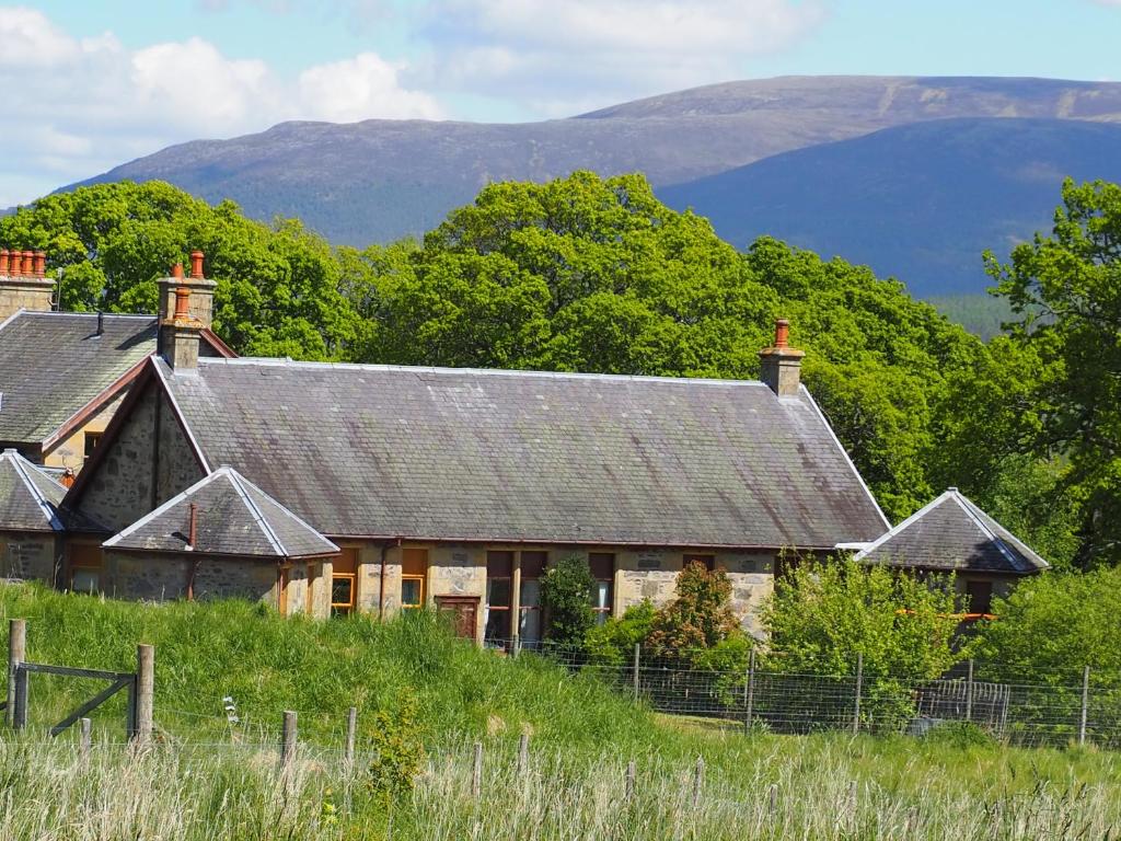 an old house on a hill with mountains in the background at Uist Cottage in Kingussie