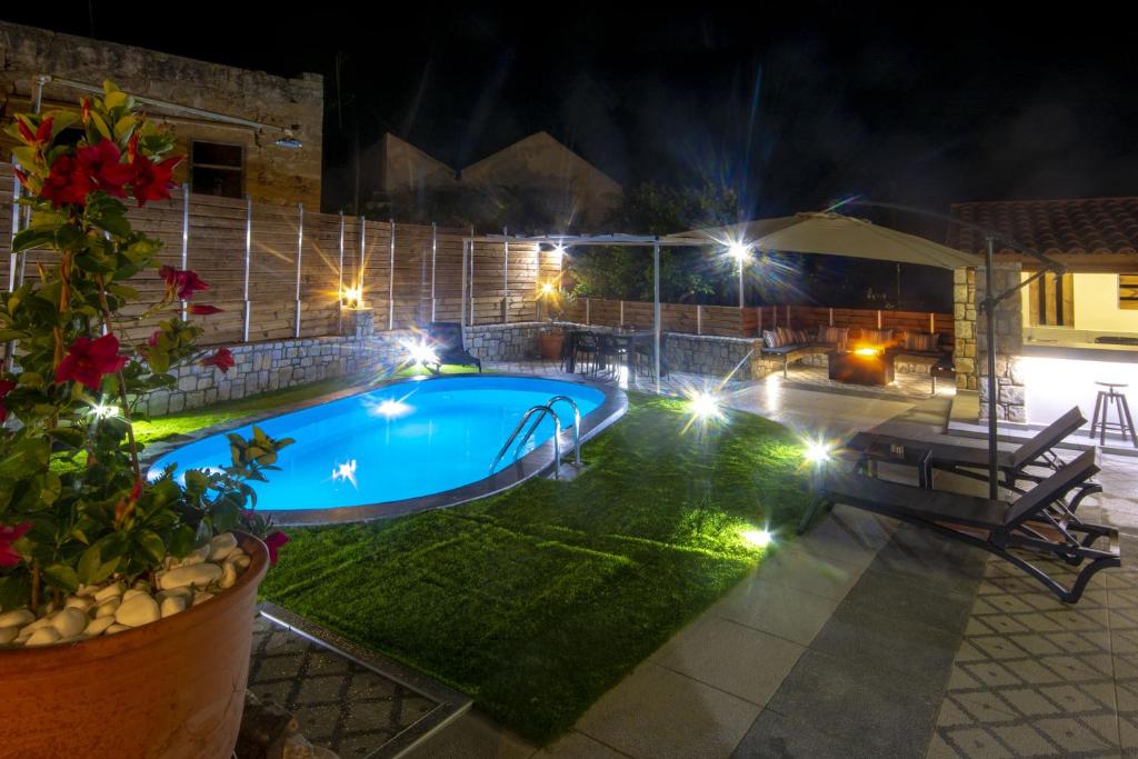 a swimming pool with lights in a yard at night at Casa Christina-Luxury Villa in Kissamos