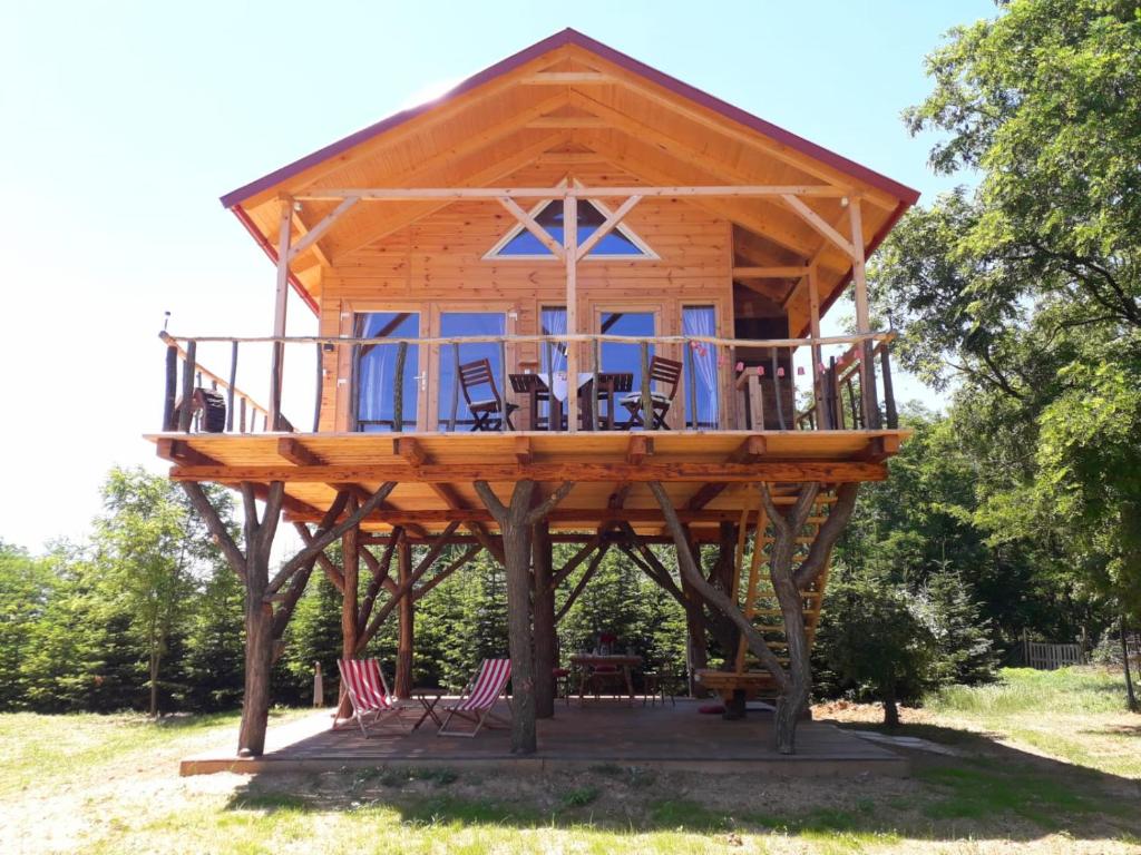 una casa en el árbol con sillas y mesas en un campo en EHM Baumhaus Chalet, en Mesteri