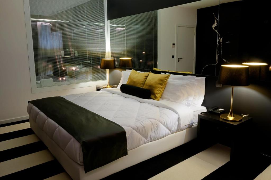 um quarto com uma grande cama branca e uma janela em Vinyl M Hotel Design Inn na Mealhada