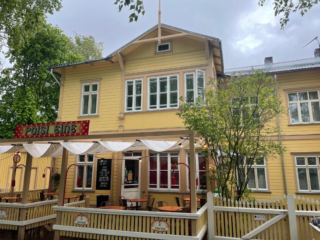 uma casa amarela com uma cerca branca à frente. em Spacious Supeluse Apartment em Pärnu