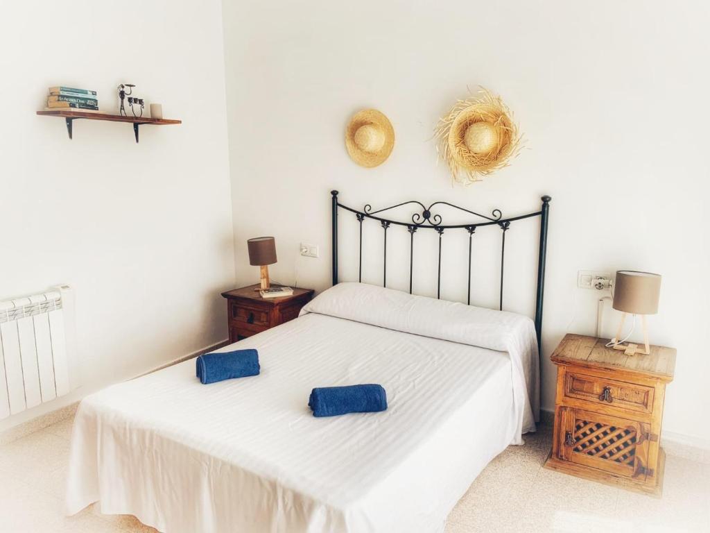 a bedroom with a bed with two blue pillows on it at Casa Barbados en Agua Amarga in Agua Amarga
