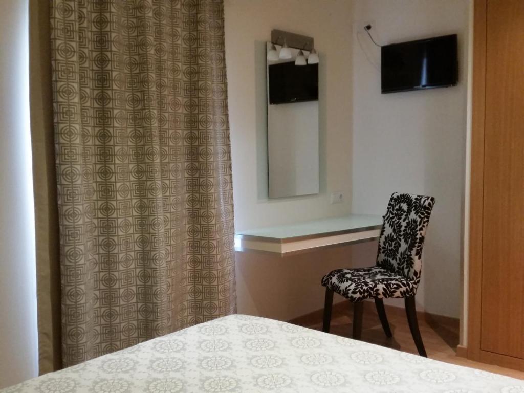 a bedroom with a chair and a mirror and a bed at Pensao Lourenco in Curia