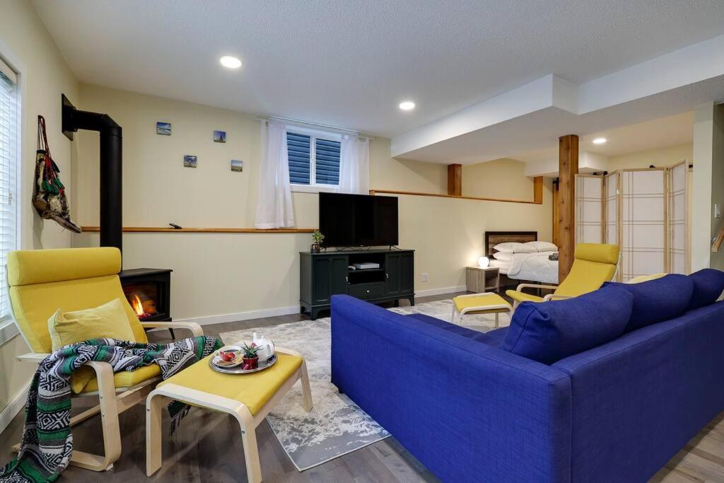 een woonkamer met een blauwe bank en gele stoelen bij Adorable private suite with indoor fire place in Cochrane
