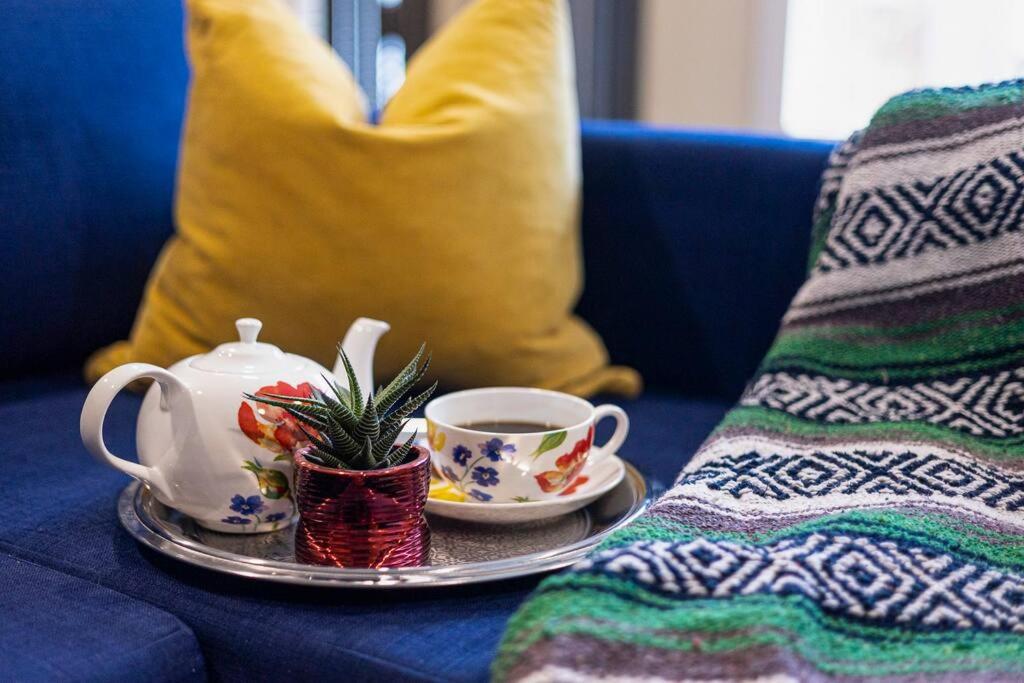 a cup of tea on a plate on a blue couch at Adorable private suite with indoor fire place in Cochrane