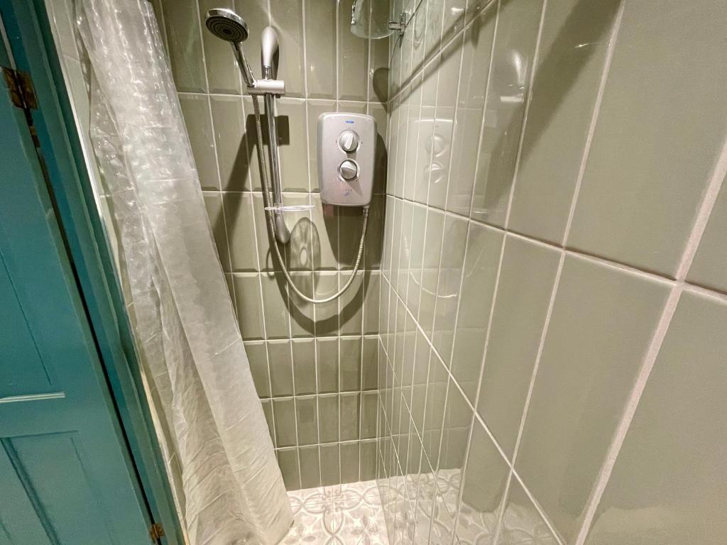 a shower with a hose in a tiled bathroom at South Road Room in Aberystwyth