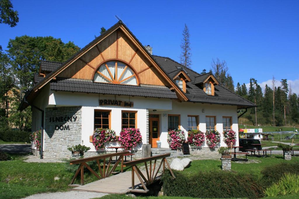 a small house with a black roof at Penzion Slnecny Dom in Tatranská Lomnica