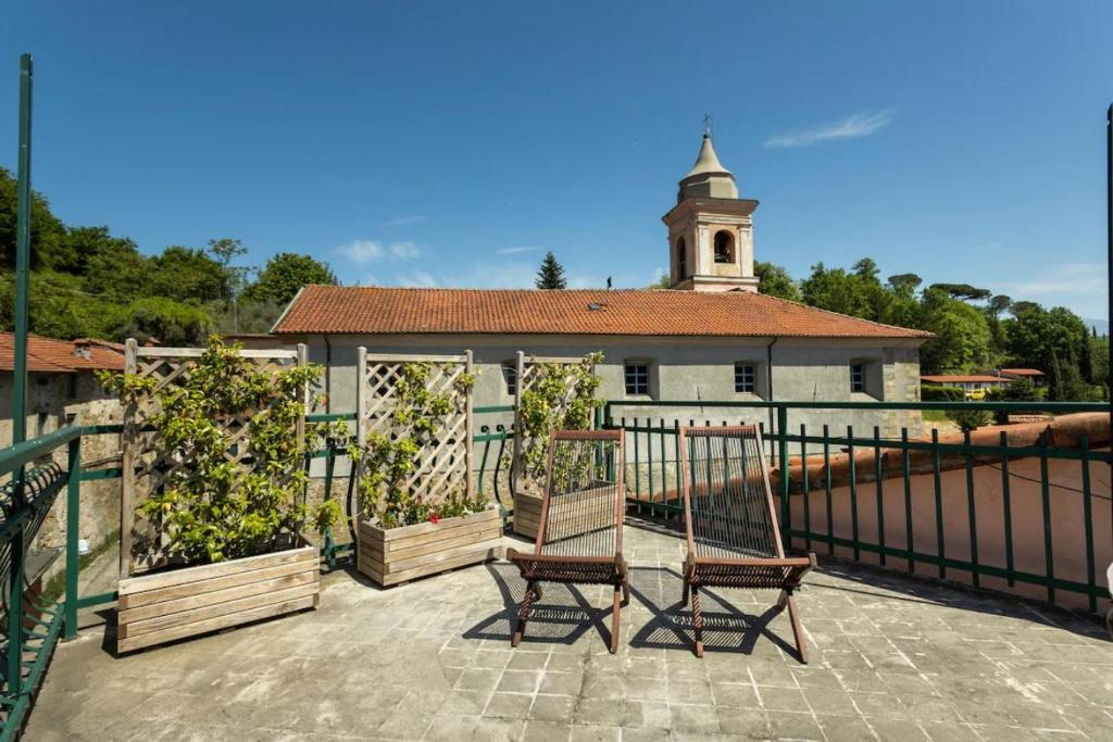 2 Stühle und ein Pavillon auf einer Terrasse mit einer Kirche in der Unterkunft La Dimora del Borgo Antico - Holiday House in Tuscany Lunigiana near 5 Terre, WiFi, Panoramic Terrace in Fivizzano