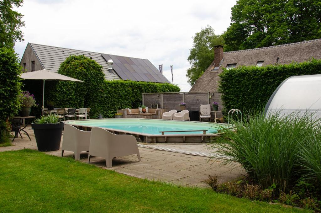 een zwembad in een tuin met stoelen en een parasol bij Bed and Breakfast Bedstay op 8 in Dalen