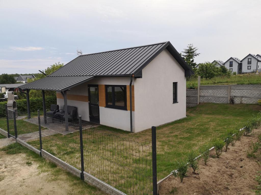 a small white house with a black roof at Domki-Apartamenty Hals in Władysławowo
