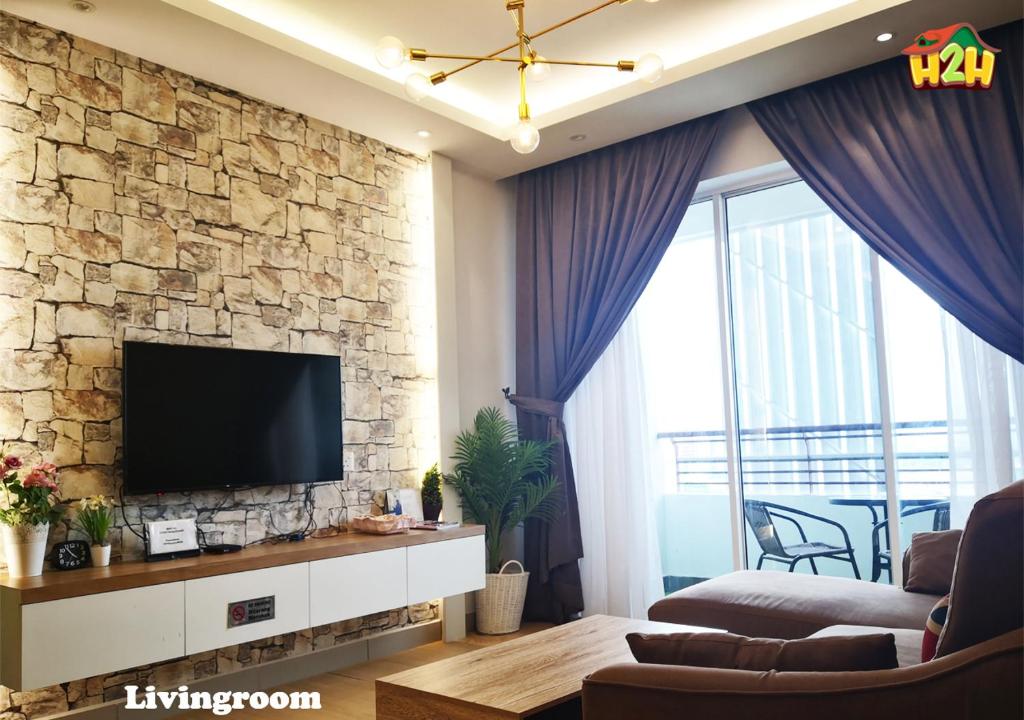a living room with a tv on a stone wall at H2H - CY15 @ Majestic Ipoh in Ipoh