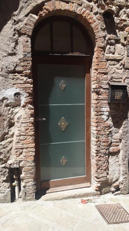 une grande porte dans un mur en pierre avec une porte verte dans l'établissement Appartamento nel Borgo, à Roccatederighi