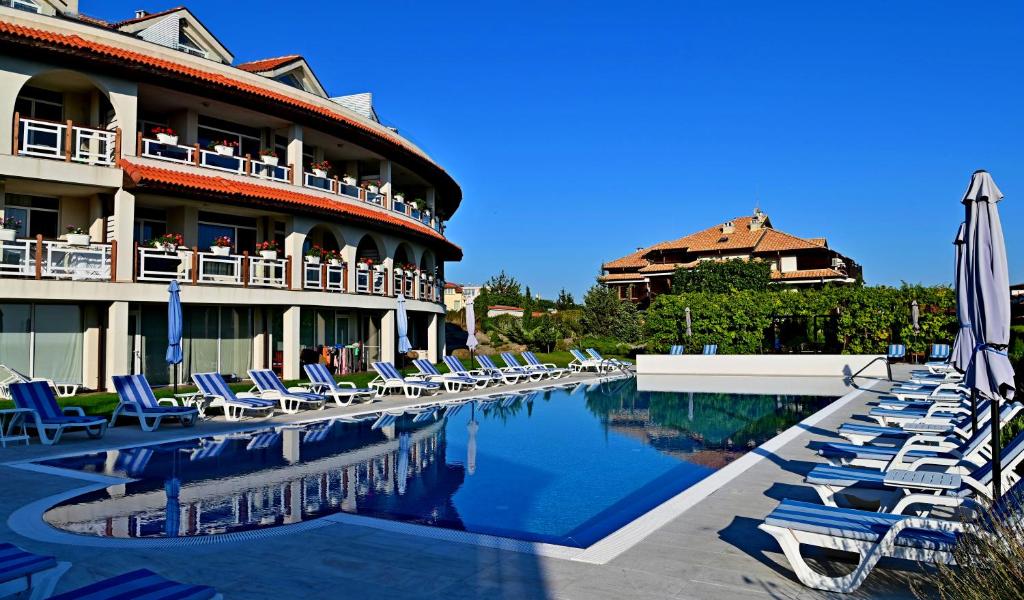 a hotel with lounge chairs and a swimming pool at Apolonia Apartments in Sozopol