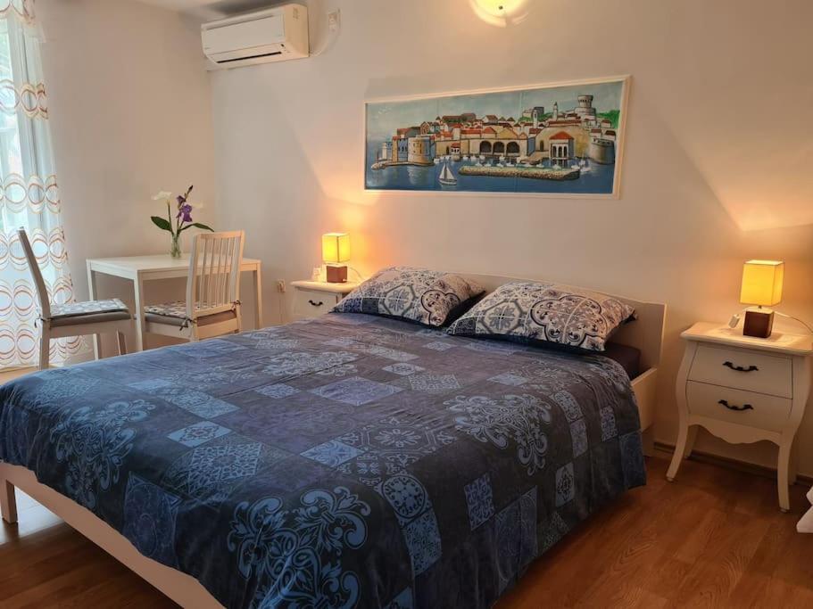 a bedroom with a bed with a blue comforter at Rooms Ljubo in Dubrovnik