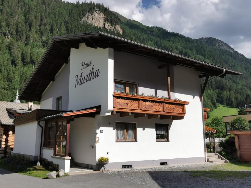 a white building with a balcony in front of a mountain at Haus Martha in Kaunertal