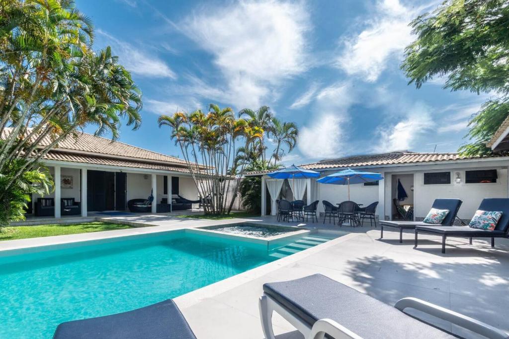 uma piscina no quintal de uma casa com palmeiras em Deliciosa casa em Geribá com hidromassagem e área gourmet em Búzios