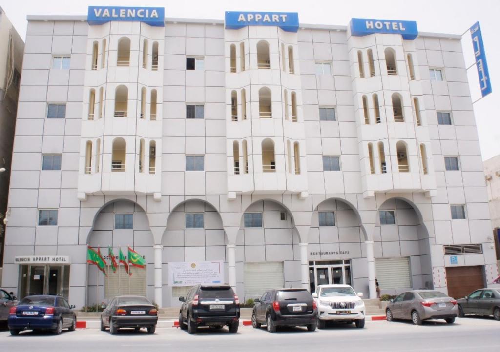 a white building with cars parked in front of it at Valencia Hôtel & Appartements in Nouadhibou