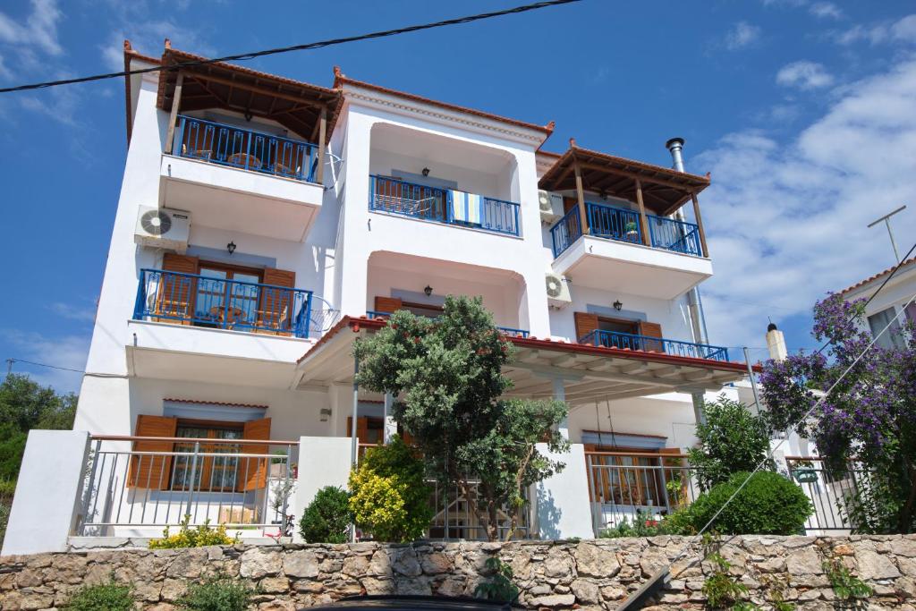 a white apartment building with blue balconies at Kavos Apartments in Patitiri