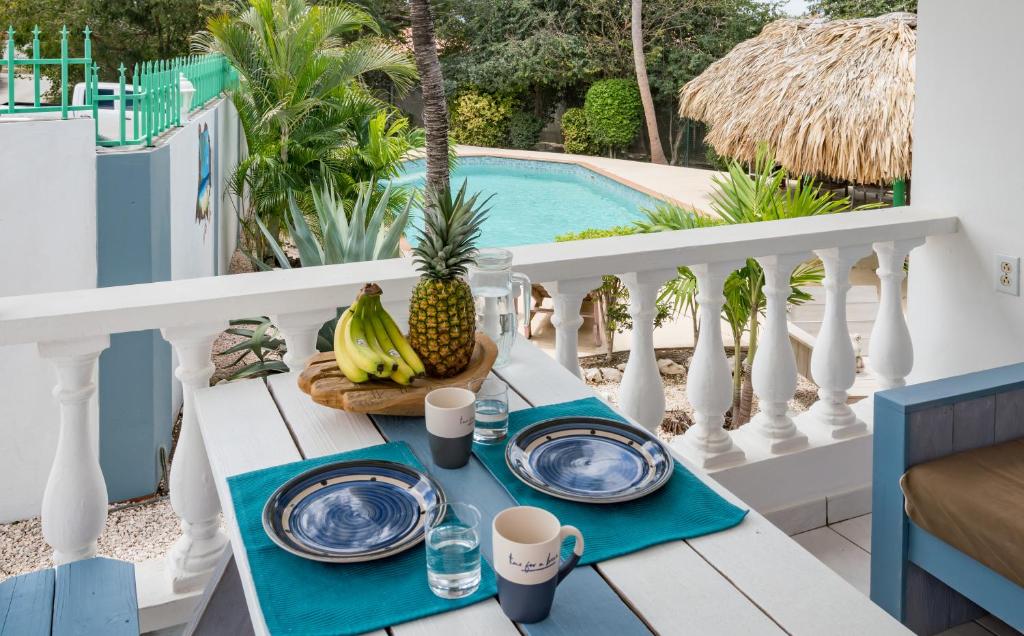 a table with plates and fruit on a balcony with a pool at The Green Turtle Eco Lodge in Willemstad