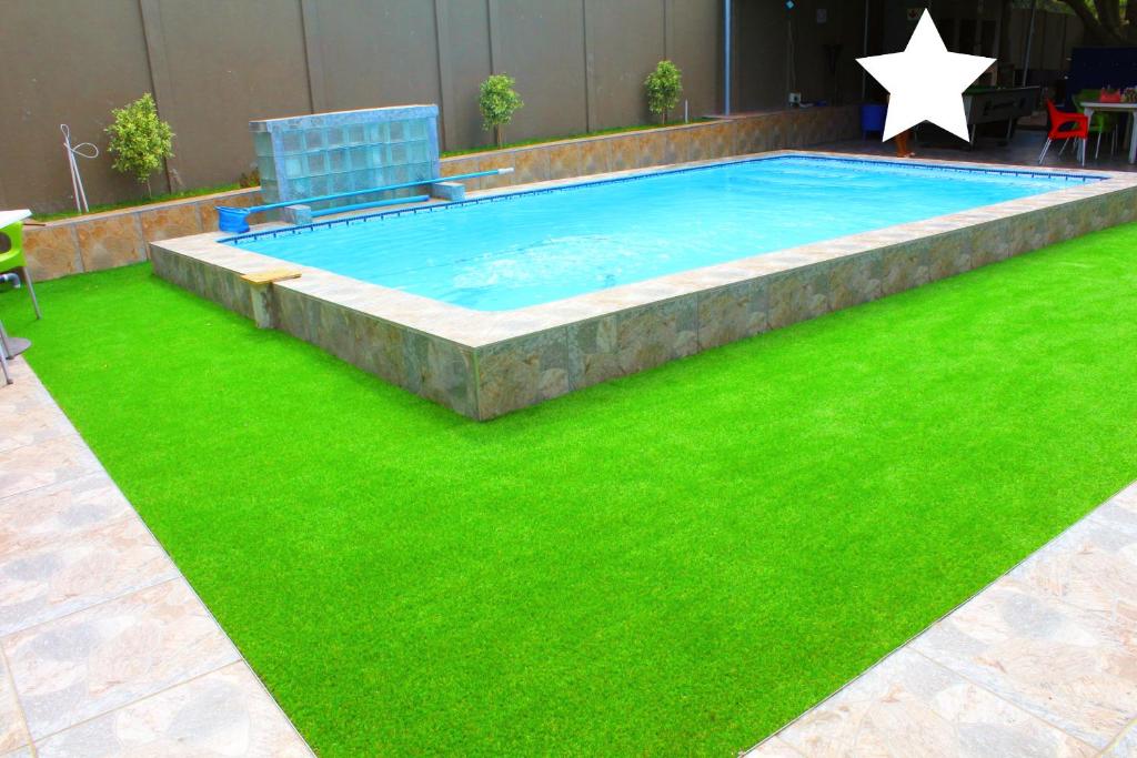 a swimming pool with green grass in a yard at MO MAJOR in Cape Town