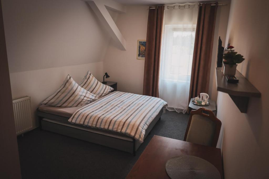 una piccola camera da letto con un letto e una finestra di Hotel Apartment Faraon a Rumburk