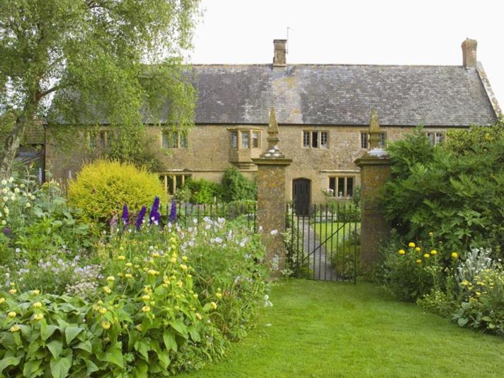 an old stone house with a gate and a garden at Lower Severalls Farmhouse in Crewkerne