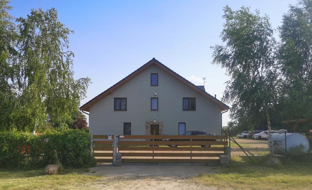 una casa bianca con una recinzione di legno di fronte di Pensjonat Ślepowron a Międzywodzie