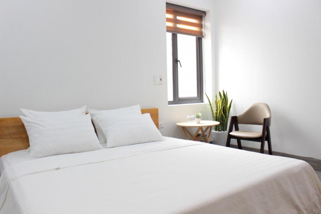 a bedroom with a white bed with a window and a chair at ᴛᴀᴍ ᴄᴏᴄ ᴄᴏᴄᴏᴏɴ ʜᴏᴍᴇsᴛᴀʏ in Ninh Binh