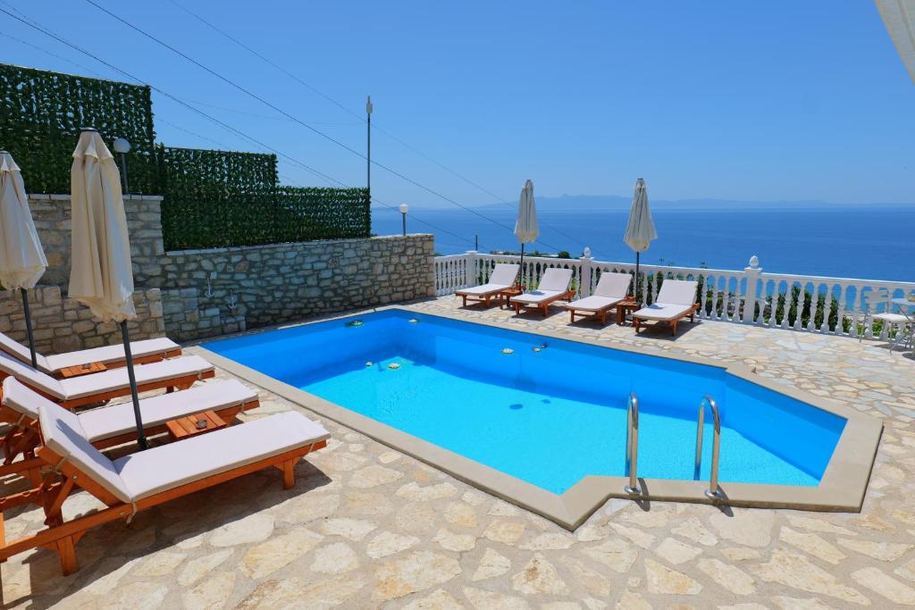 a swimming pool with chaise lounge chairs and a swimming pool at Sunset villas in Qeparo