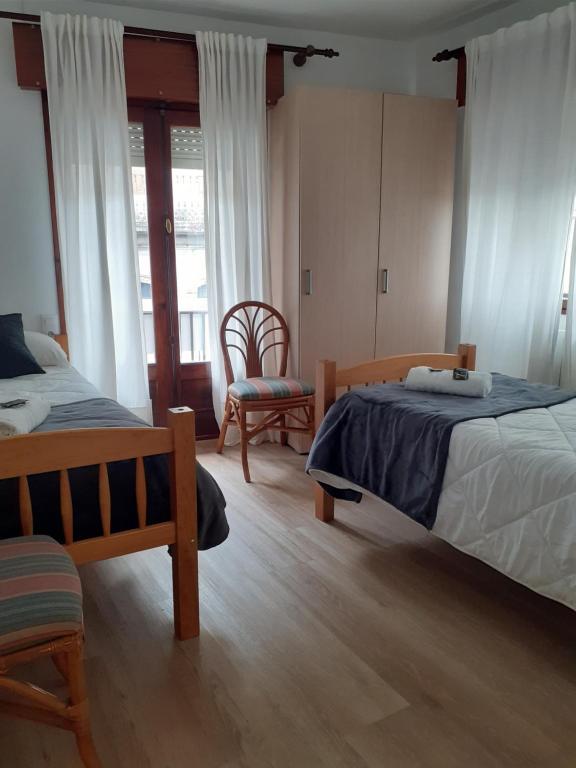 1 dormitorio con 2 camas y 1 silla en Pensión Río Umia, en Caldas de Reis
