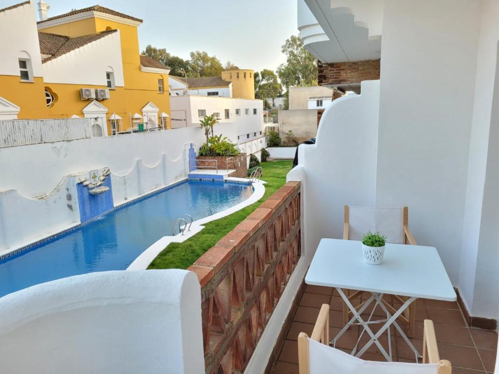 balcón con mesa y piscina en Apartamento en Rota con piscina y parking junto al mar en Rota