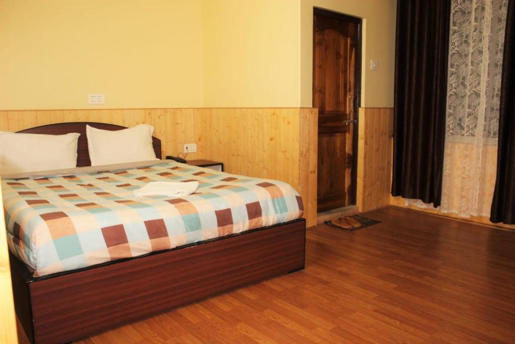 a bedroom with a bed with a wooden floor at Hotel Seren Point in Kalimpong