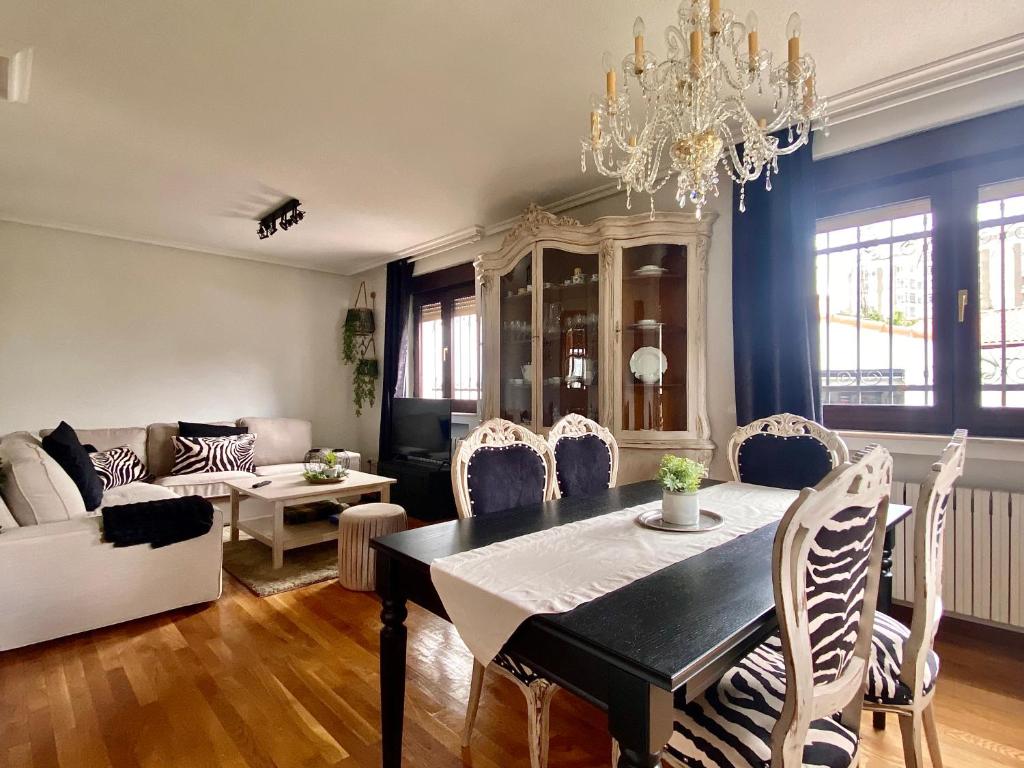 a living room with a table and chairs and a chandelier at Housing León Casa con Jardín in León