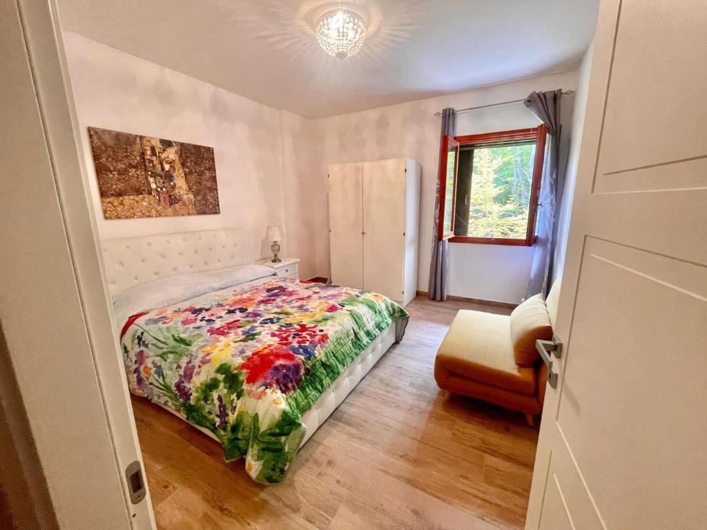 1 dormitorio con 1 cama y 1 silla en La Tana del Capriolo, en Prati di Tivo