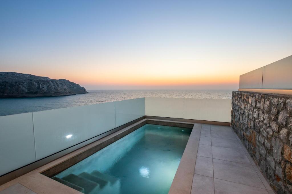 a swimming pool with the ocean in the background at Thalasidi Luxury Suites in Karpathos