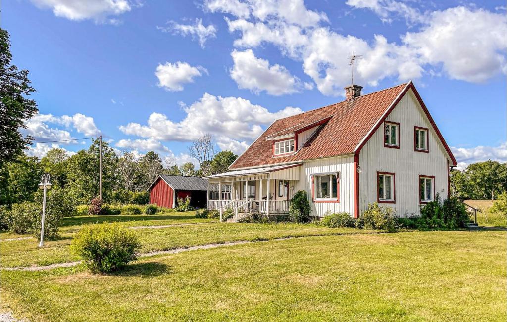 a white house with a red barn in a yard at Awesome Home In Karlskrona With Wifi And 3 Bedrooms in Karlskrona