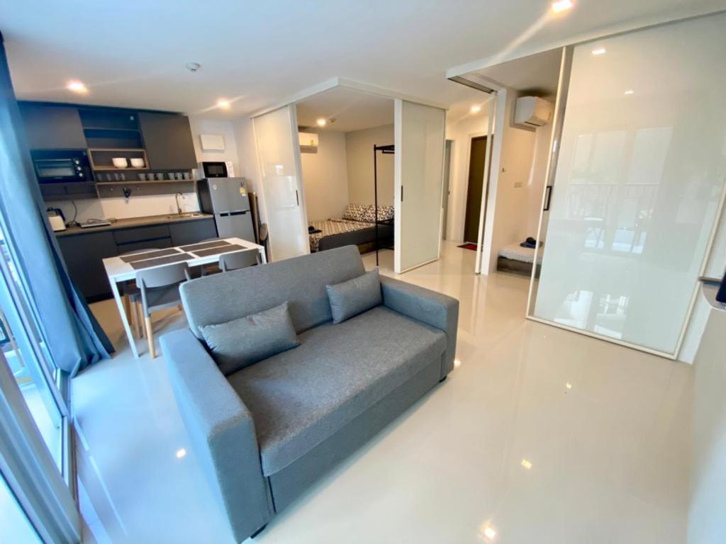 a living room with a blue couch and a kitchen at Mantra Beach Condominimum, 2 bedrooms, Laem Mae Phim Beach in Klaeng