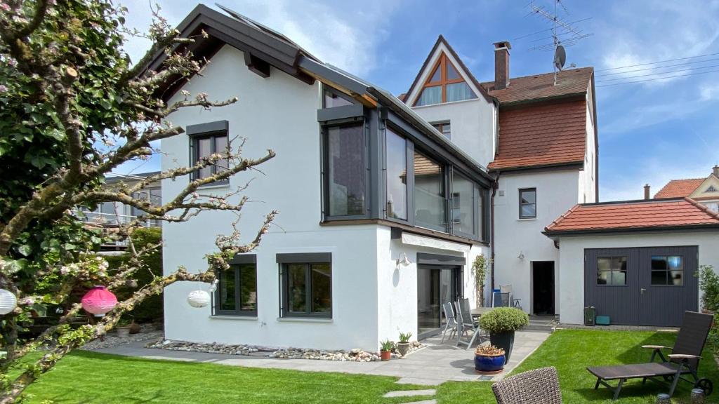 een wit huis met zwarte ramen en een tuin bij Ferienwohnung Mayer in Bad Schussenried