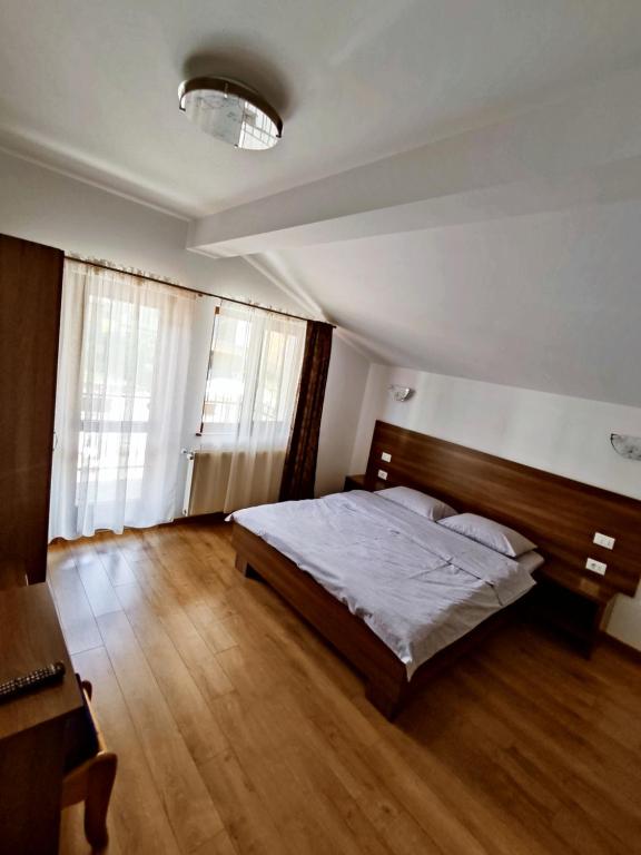 1 dormitorio con 1 cama y suelo de madera en Pensiunea ANCA en Statjunea Borsa