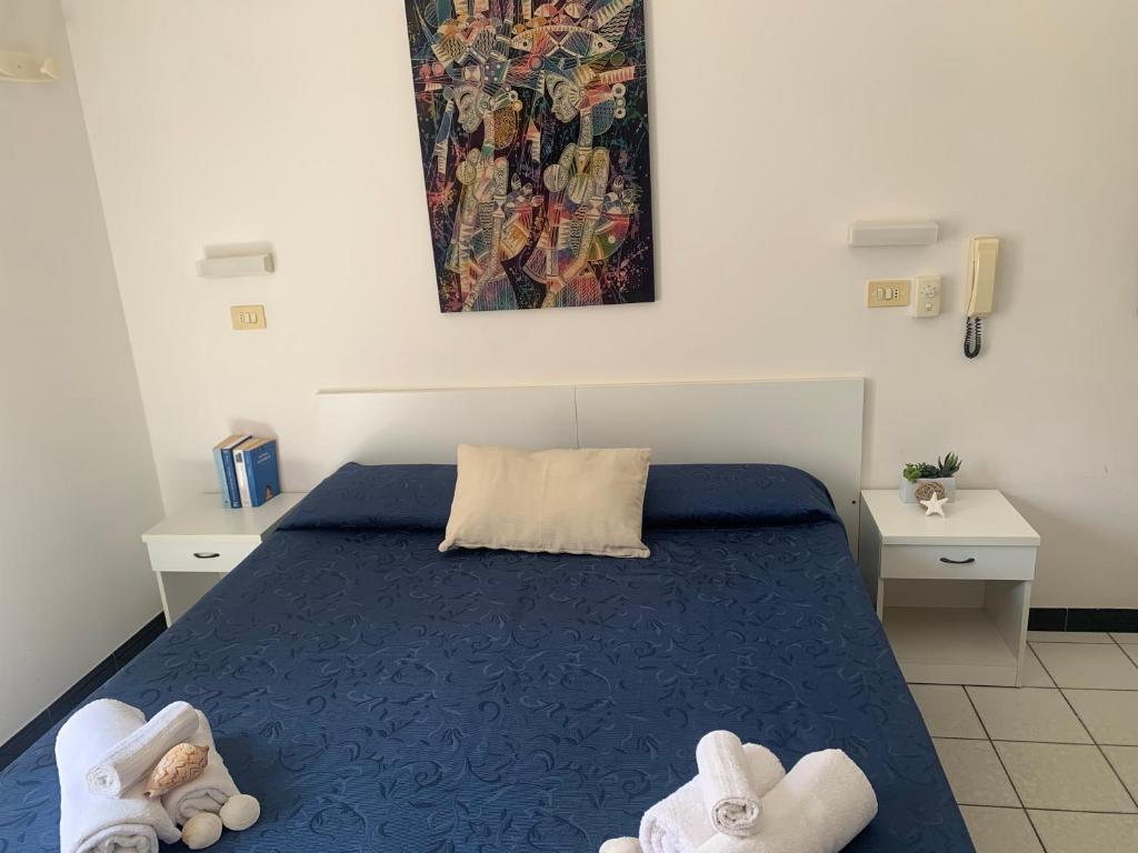1 Schlafzimmer mit einem blauen Bett und 2 weißen Tischen in der Unterkunft HOTEL LA PERGOLA in Cattolica
